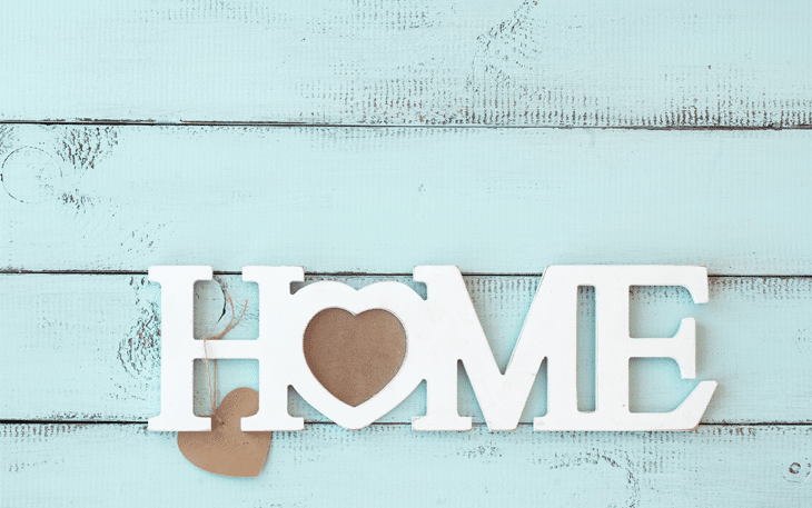 Home cut out white words against a blue wood background.