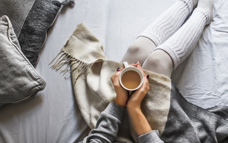 Lady covered with blankets drinking coffee