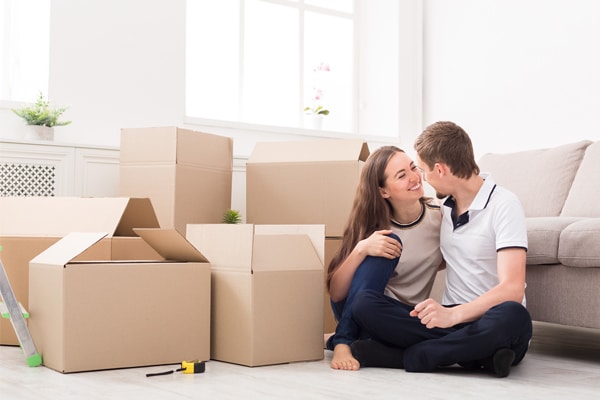 Young couple unpacking moving boxes in new apartment, copy space