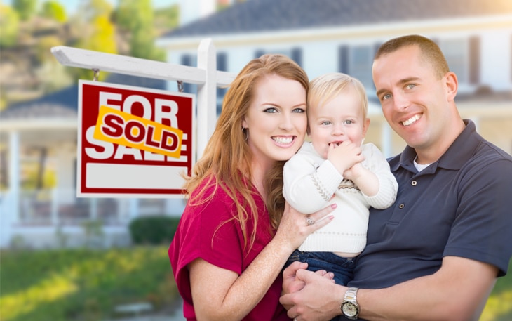 Picture of couple with daughter in front of sold sign