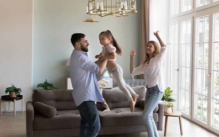 Young family dancing in their living room.